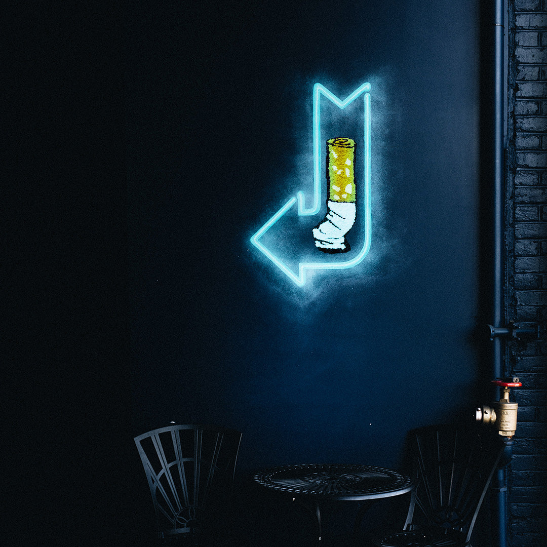 studio yarnatak cigarette butt small wall rug in dark room with neon blue light arrow
